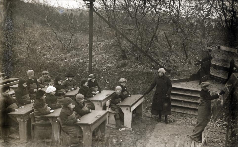 Children at school desks that have been set outside at tuberculosis preventorium