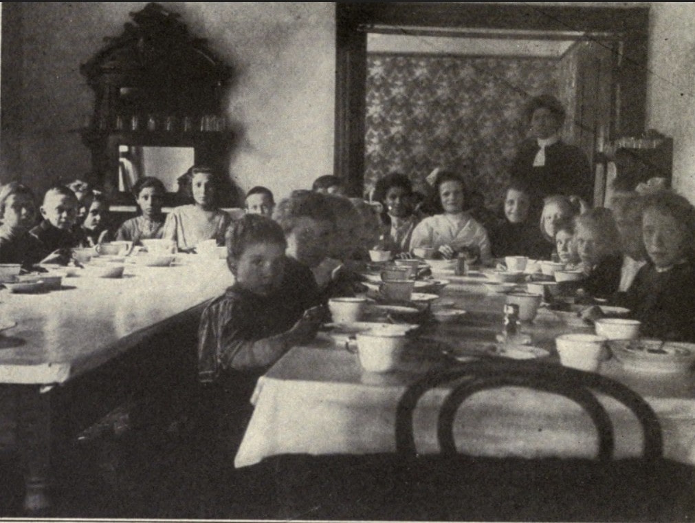 Children at tables in a tuberculosis preventorium dining room