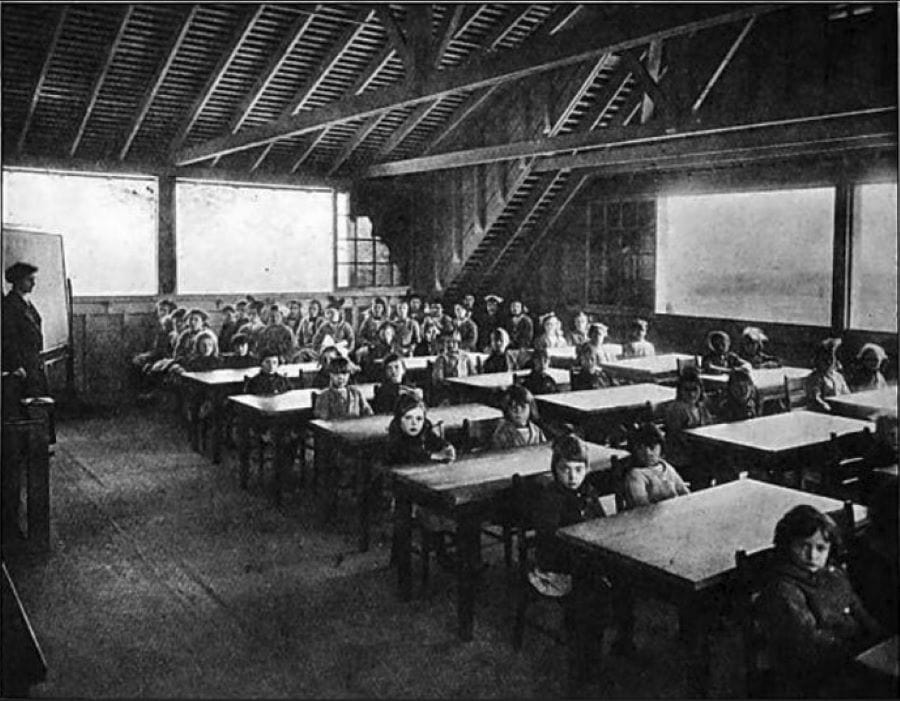 Children in a school room with large, open windows.