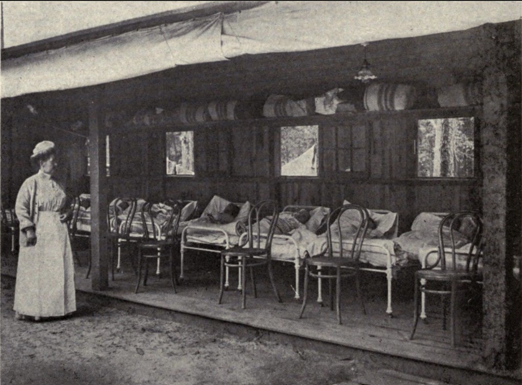 Boys resting in a line of beds, overseen by tuberculosis preventorium nurse