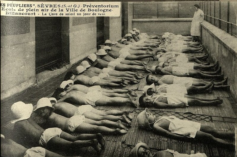 Children in light clothing laying on a porch at tuberculosis preventorium